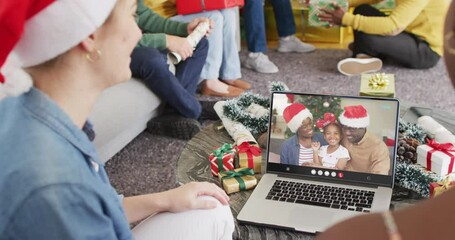 Wall Mural - Diverse friends with santa hats having laptop video call with african american family