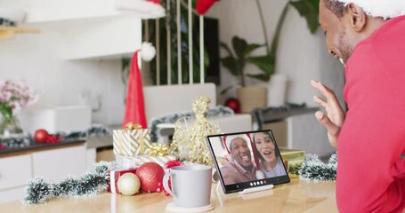 Wall Mural - African american man with christmas decorations having video call with diverse couple