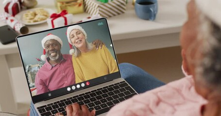 Wall Mural - Senior african american woman having christmas video call with senior diverse couple