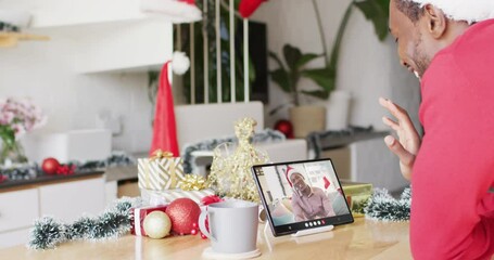 Canvas Print - African american man having christmas video call with african american man