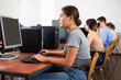 © JackF - Side view on focused teenager female student sitting at desk in computer class in library, preparing for exam