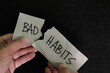 Breaking bad habits concept. Human hand tear a paper with word bad habit in dark black background. 
