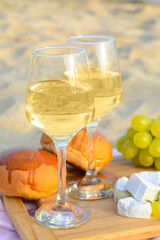 Wall Mural - Glasses with white wine and snacks for beach picnic on sand outdoors
