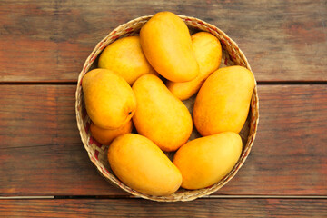 Delicious ripe juicy mangos on wooden table, top view