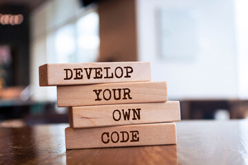 Wall Mural - Wooden blocks with words 'Develop your own code'.