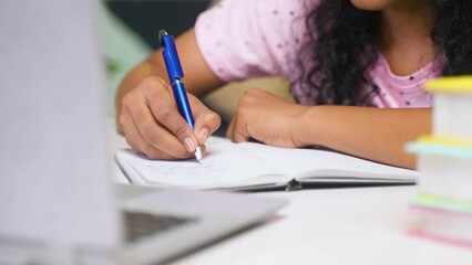 Close up shot of girl student making notes from online class using laptop at home - concept of learning, technology and education