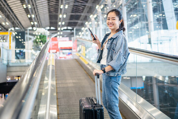 Asian woman traveler walking dragging a suitcase to gate in airport