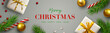 Christmas background with Christmas decor including lights, baubles, gift box, fir tree cuttings, glitter, berries and candy cane.