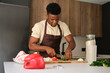 © Ladanifer - Young black man cutting celery to prepare chicken recipe in a kitchen.
