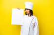 Young chef latin woman isolated on yellow background holding an empty placard and looking it