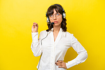 Telemarketer latin woman working with a headset isolated on yellow background