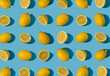 Summer pattern made with fresh cut and whole yellow lemon on bright light blue background. Minimal background summer concept on with harsh light and sharp shadow
