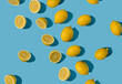 Diagonal summer pattern made with fresh yellow and lemon slices on bright blue pastel background. Minimal background summer concept on bright sunlight with sharp shadows