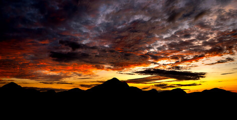 Wall Mural - panorama abstract dark cloud sunset over dark mountain.colorful sunrise with clouds over hill.sun hi