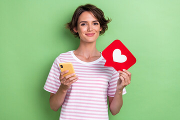 Sticker - Photo of charming positive lady trendy outfit arm hold telephone red paper heart recommend device gadget isolated on green color background