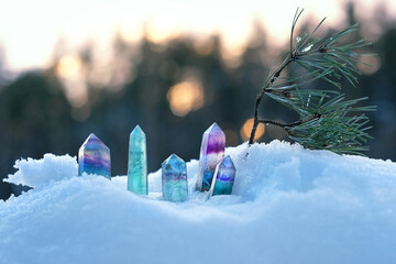 Crystals gemstones and pine branch on snow, natural winter background. minerals for esoteric Crystal Ritual, Witchcraft, spiritual energy practice in winter season. reiki healing therapy