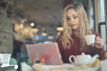 young woman in a cafe works at a computer