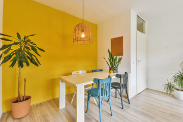 a dining room with yellow walls and wooden flooring, two blue chairs and a white table in the corner