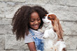 © Anna Zhukkova - Portrait happy african american child holding pet dog on wall background