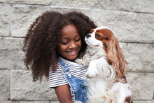 Portrait Happy African American Child Holding Pet Dog On Wall Background