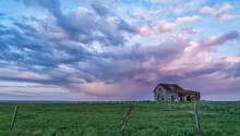 Old Farmstead On The Prairies Under Glowing Storm Clouds At Sunset; Val Marie, Alberta, Canada