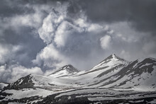 Snow Covered Mountain Peaks Under A Cloudy Sky Along The Dempster Highway Near Dawson City; Yukon, Canada