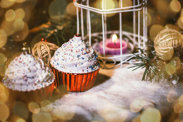 Wall Mural - cupcakes,Christmas candle and Christmas decorations on wooden background. beautiful bokeh effect from a garland.