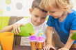 © spyrakot - Two kids make ice cream from fruit juice on table at home