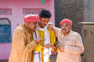 Three Indian villagers watching some detail in smartphone.