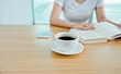 © xy - Woman reading book with cup of coffee on table