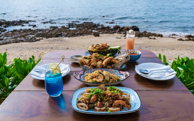 Wall Mural - Dinner table with Thai food and bbq fish on the beach of Pattaya Thailand.