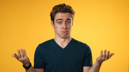 Portrait of happy young man 20s shrugging shoulders and gesturing I do not know isolated on yellow background.