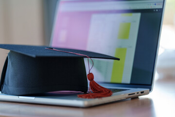 Wall Mural - Graduation cap with laptop pace on wood table background.
