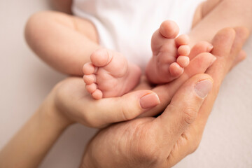 children's foot in the hands of mother, father, parents. feet of a tiny newborn close up. little bab