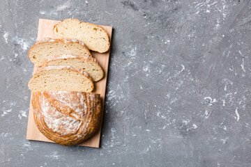 Freshly baked bread slices on cutting board against white wooden background. top view Sliced bread