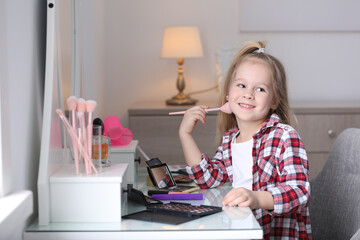 Wall Mural - Adorable little girl applying makeup at dressing table indoors