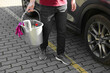 © New Africa - Man holding bucket with car cleaning products outdoors, closeup