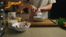 Video. Festive Home Kitchen Interior. A Young Man Prepares A Dish Of Mushrooms. Presses The Garlic Into A Bowl. On The Table Prepared Mushrooms, Cheese. Milk, Greens.