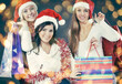 © yurolaitsalbert - group of happy women in costumes of Santa Claus and Christmas shopping.