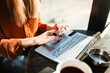 © Nikola Spasenoski - Young businesswoman in a cafe bar or restaurant with bright sunlight. Freelancer girl working on laptop and having tea at a window table. Abstract photo..