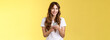Enthusiastic charming sociable young girl messaging friend sending photos social media hold smartphone look camera happily friendly smiling stand yellow background casual outfit