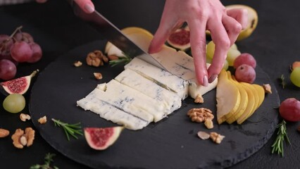 Wall Mural - Woman slicing Traditional Italian Gorgonzola cheese on stone seving board