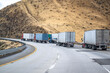 Big rigs semi trucks with loaded semi trailers slowly climbing uphill on the highway road to mountain pass in California