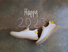 Happy 2023 new year template made from white shoes and shoe lace with textured background. New year template for footwear businesses. 