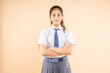 Happy confident Indian student schoolgirl wearing school uniform standing cross arm isolated over beige background, Studio shot, closeup, Education concept.