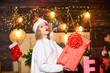 © be free - Little Christmas magic. cheerful girl share xmas gift. winter holidays and vacation. Christmas shopping. merry christmas. happy new year. Celebrating xmas with family. woman in santa hat present box