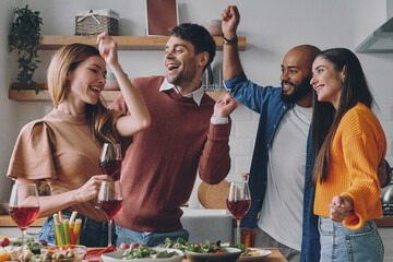 Wall Mural - Cheerful young people dancing and smiling while enjoying party at home together