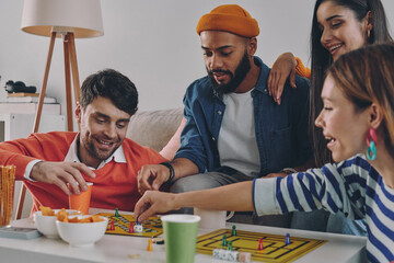 Wall Mural - Cheerful young people playing board game while enjoying carefree time together