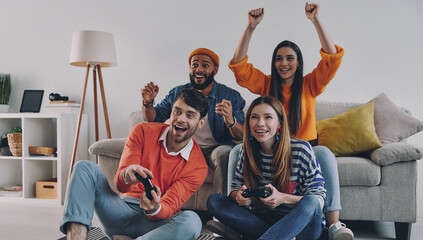 Wall Mural - Beautiful young people playing video games and smiling while enjoying carefree time together