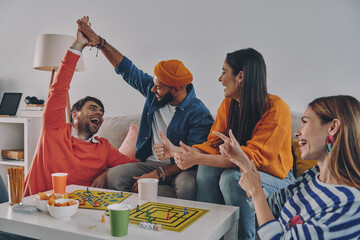 Wall Mural - Happy young people playing board game while enjoying carefree time together